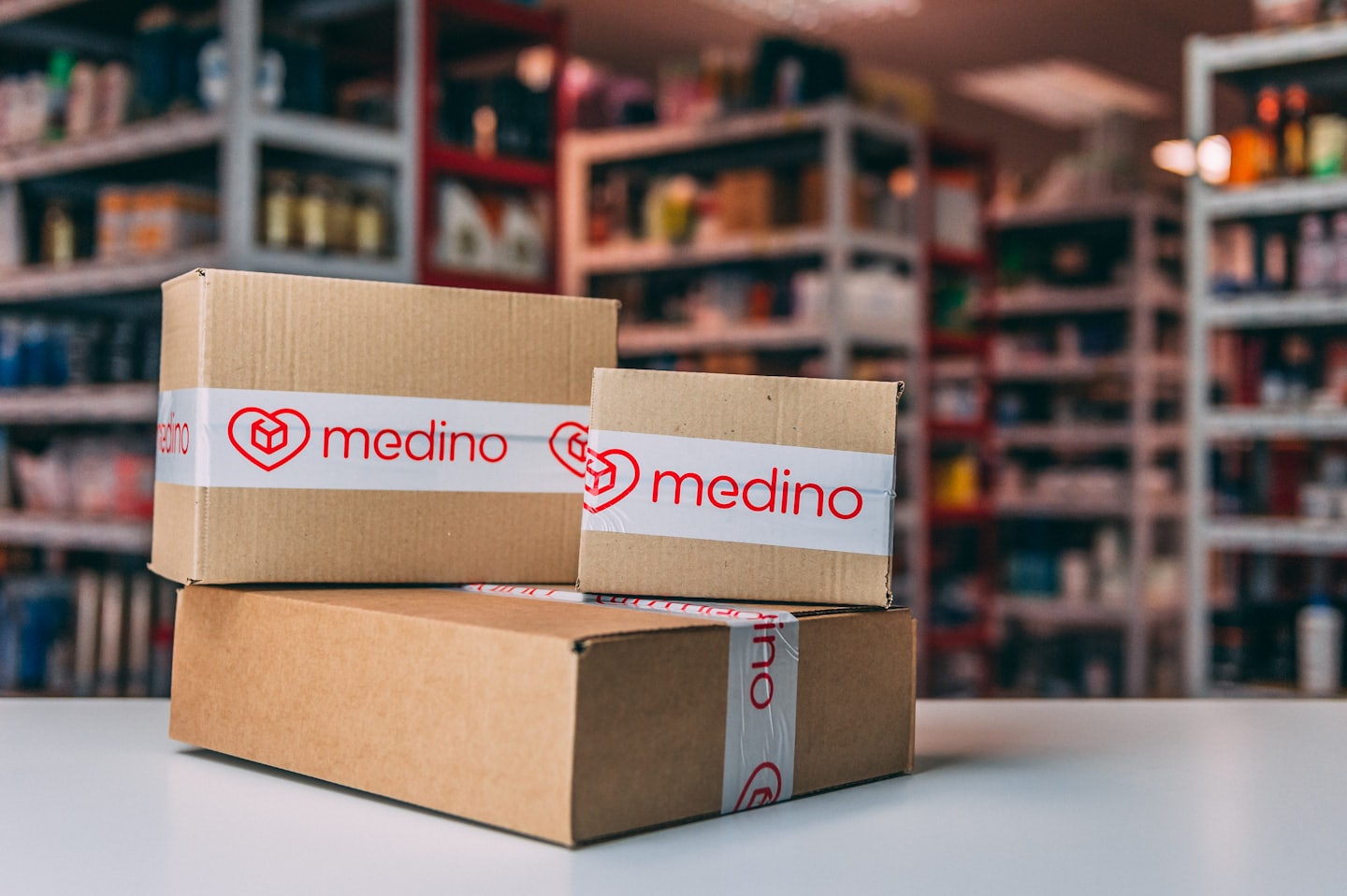 Three sealed cardboard boxes with red logos stacked on a white surface.